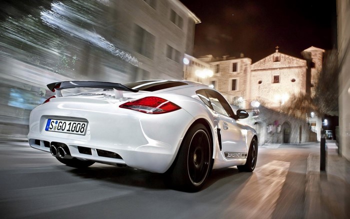 White Porsche Cayman driving on a street at night
