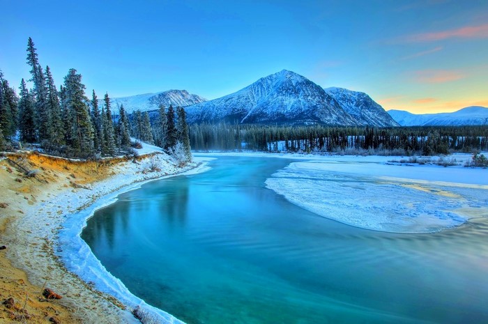 Winter landscape with snow-covered mountains and a flowing river