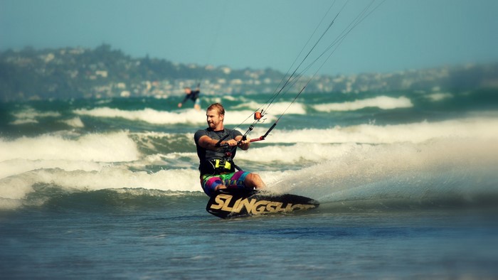Man kite surfing on a wave with a Slingshot board