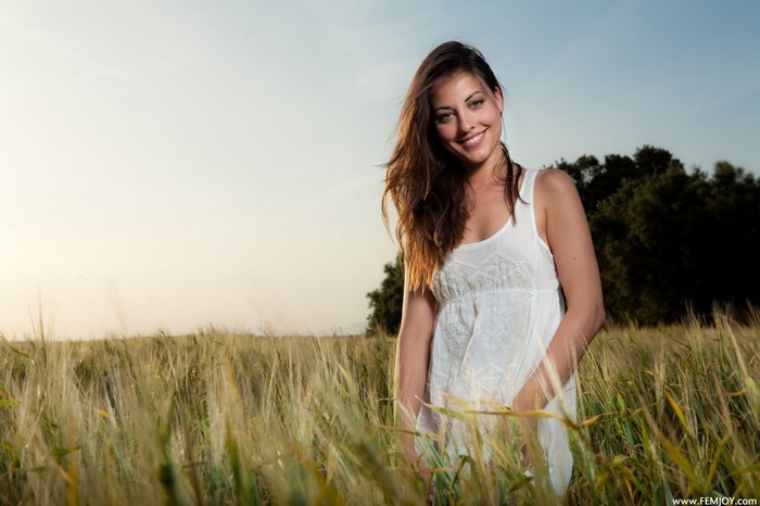 Smiling Woman in White Dress in Sunlit Field