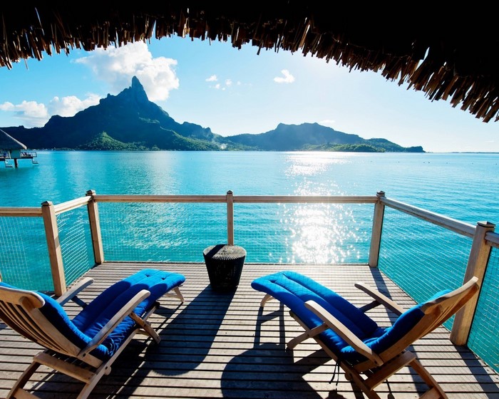 Deck chairs overlooking turquoise water and a tropical mountain