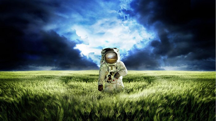 Astronaut in a green field under stormy clouds