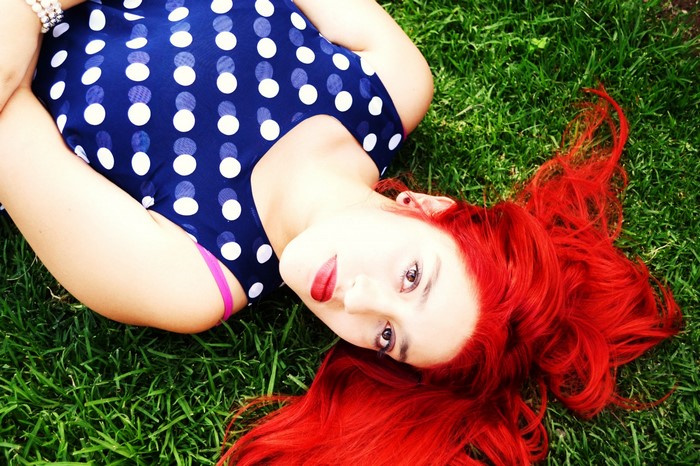 Woman with red hair lying on grass