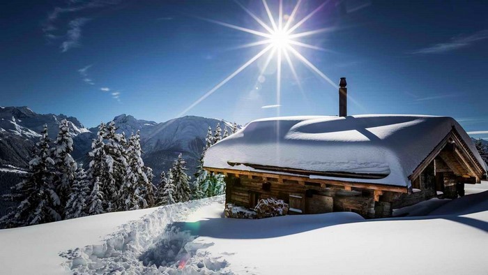 Snowy cabin in the mountains with sun