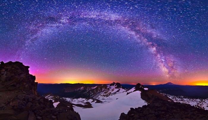 Milky Way over snow-capped mountains at dawn