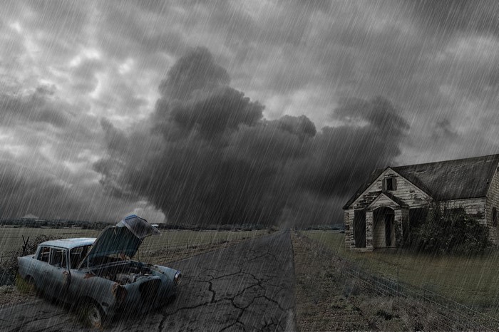 Stormy rural landscape with abandoned car and building