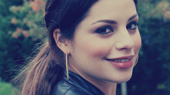Woman with brown hair and gold earring smiling
