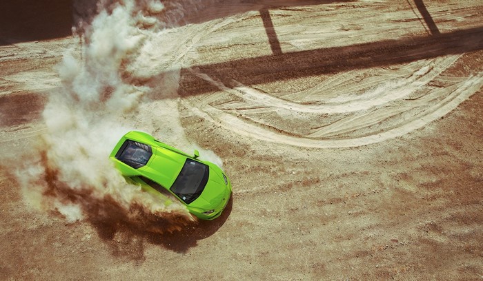 Green Lamborghini Huracan drifting in dust