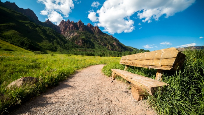 Wooden bench on a path with mountains