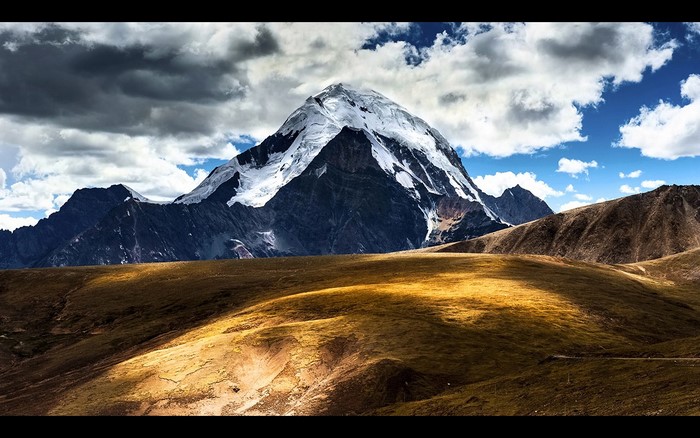 Snow-capped mountain range under a cloudy sky