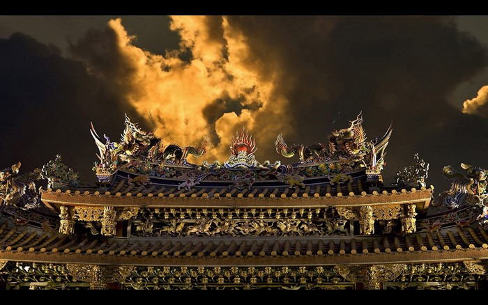 Ornate Chinese temple roof with dragons at night