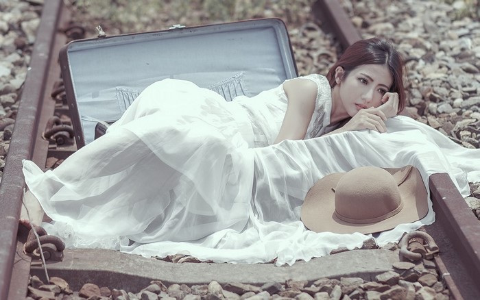 Woman in White Dress Lying on Railway Tracks