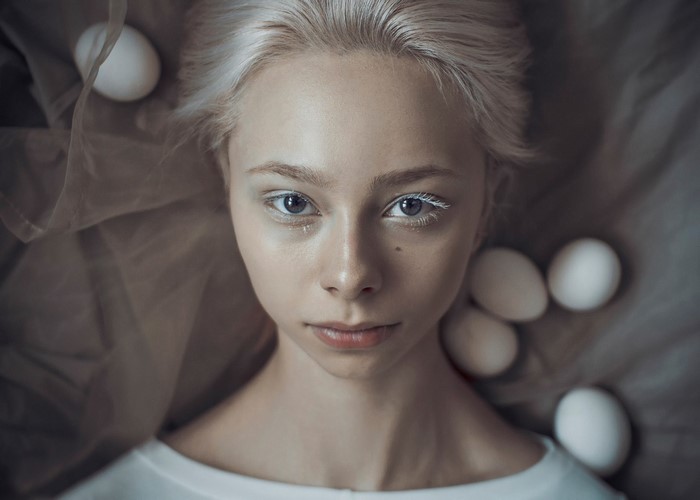 Portrait of a young woman with white eyelashes and eggs