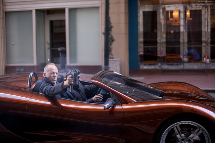 Bruce Willis in a car shooting a gun