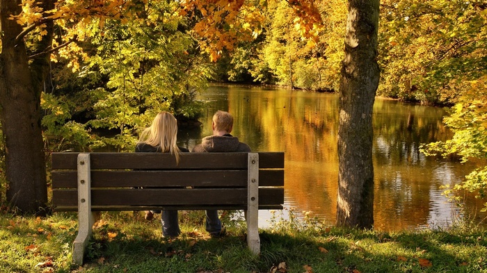Couple sitting on a bench by a lake in autumn