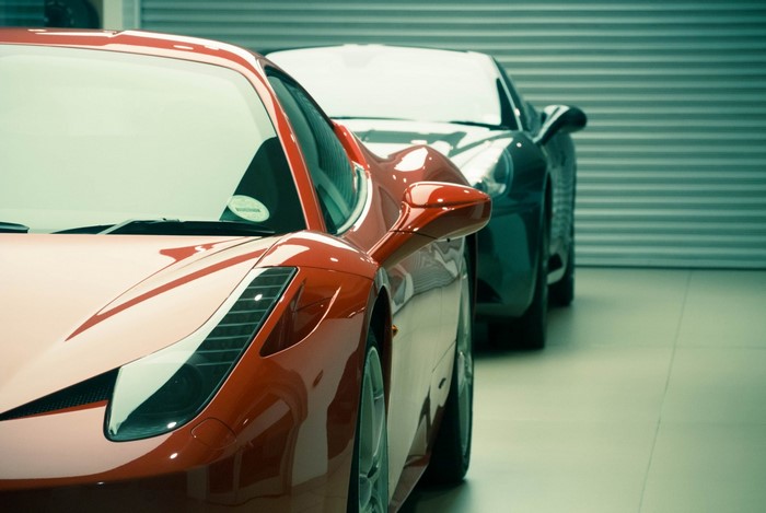 Red Ferrari 458 and dark sports car in garage