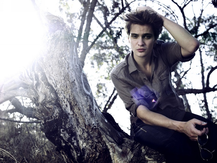 Luke Grimes sitting on a tree branch
