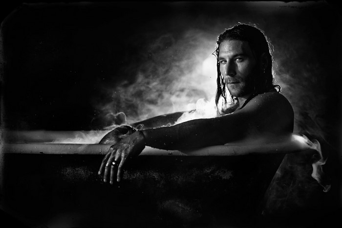 Man with long hair in a bathtub with steam