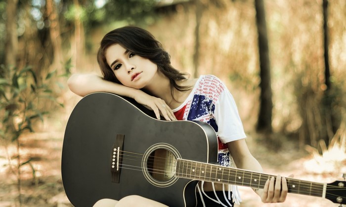 Asian woman with guitar in forest