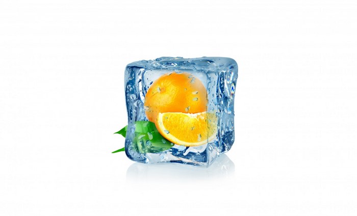 Orange fruit and slice frozen in ice cube with leaves