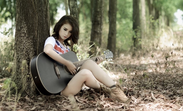 Woman playing guitar in a forest