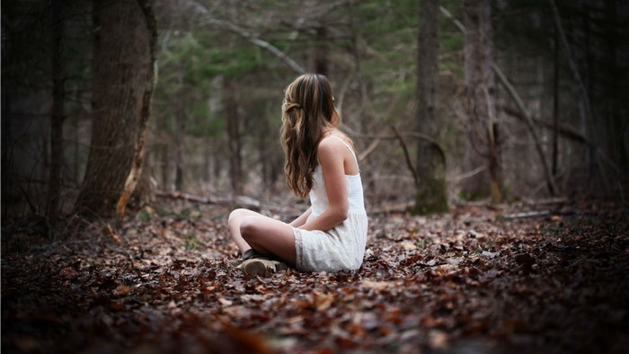 Woman sitting in a forest during fall