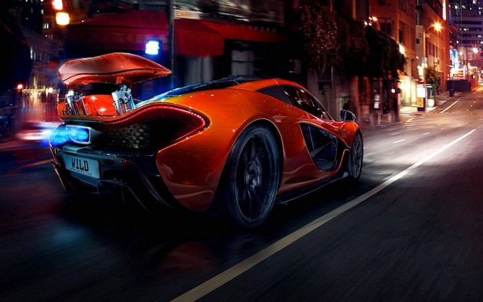 McLaren P1 driving through a city at night