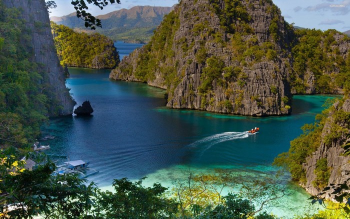 Boat navigating a tropical bay with limestone cliffs
