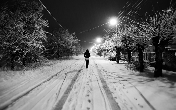 Woman walking on a snowy street at night