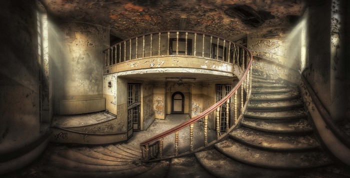 Abandoned Interior with Curved Staircase and Sunlight