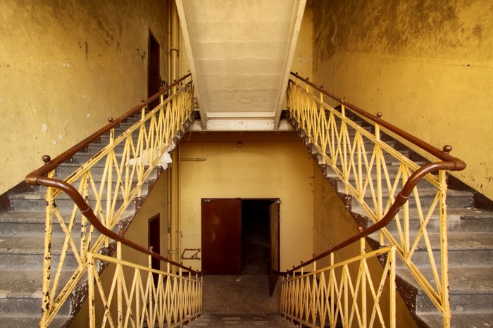 Abandoned building interior with yellow walls and staircases
