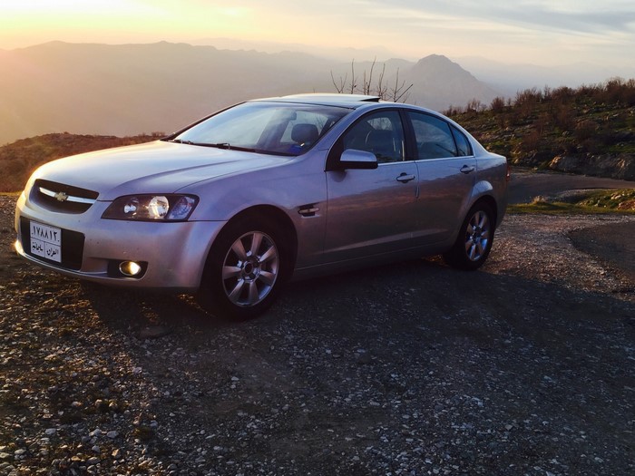 Silver Chevrolet Lumina Sedan parked on a mountain road at sunset