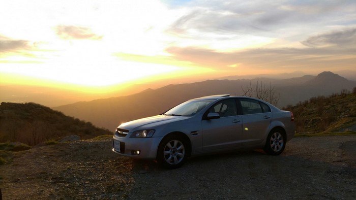 Silver Chevrolet Sedan on a Mountain Road at Sunset