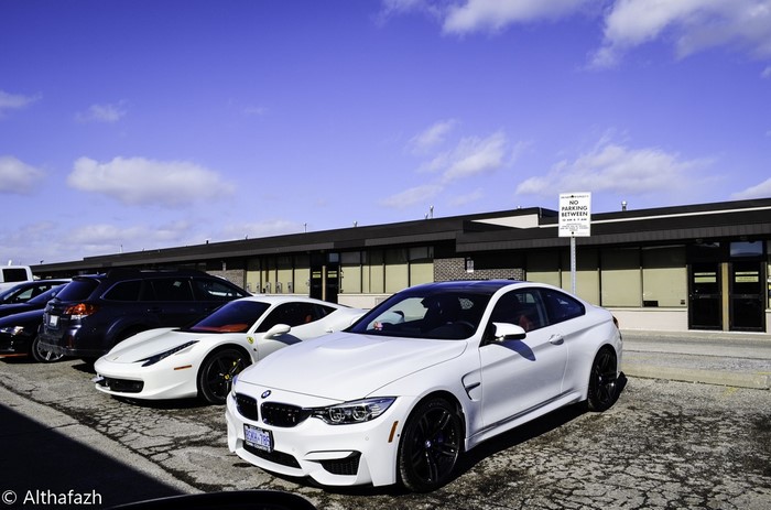 White BMW M4 Coupe and Ferrari 458 parked
