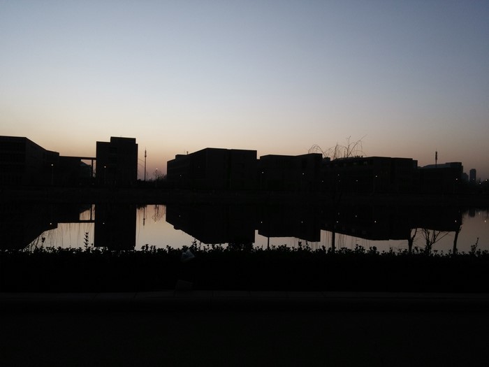Silhouette of buildings reflected in water at dusk