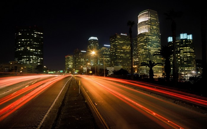 Cityscape at night with light trails on a highway