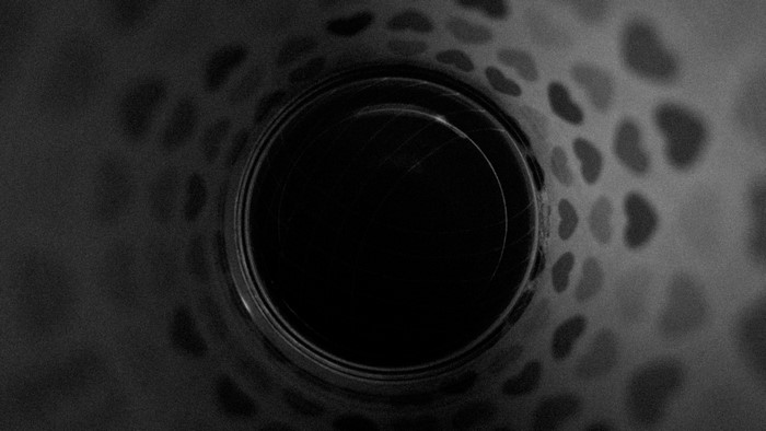 Monochrome close-up of a dark circular opening with heart-shaped patterns