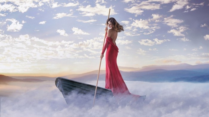 Woman in red dress in a boat on clouds