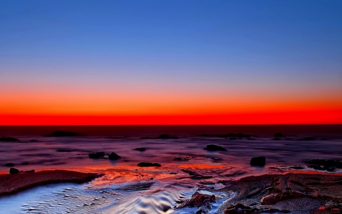 Sunset over the ocean with a rocky shore