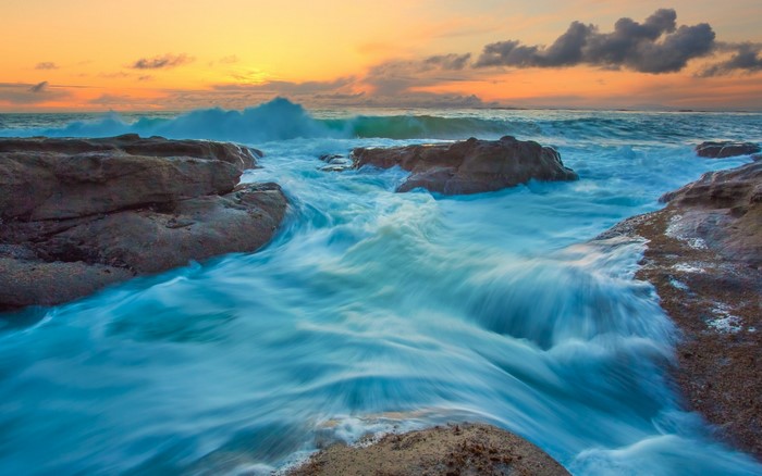 Ocean waves crashing on rocks at sunset