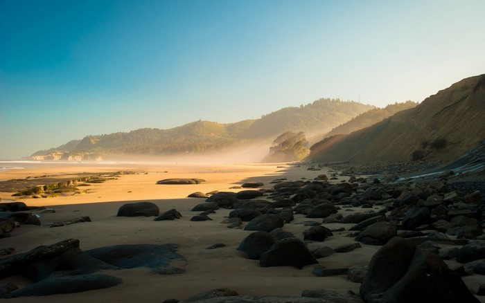 Beach with mountains and fog at sunrise