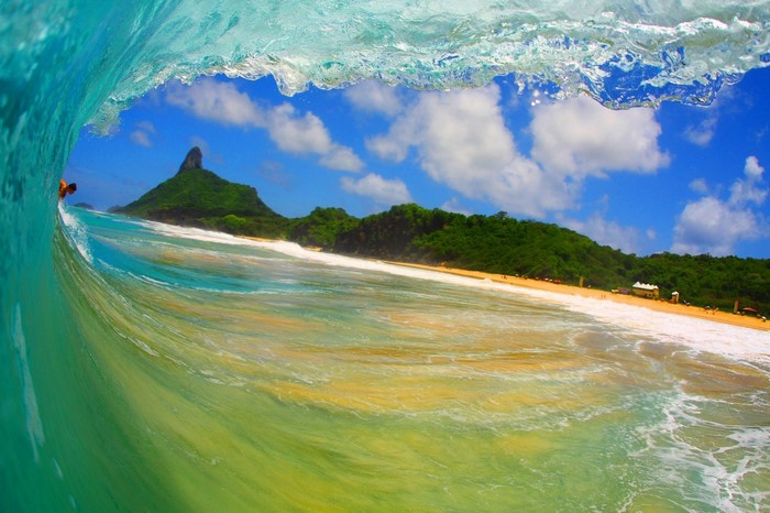 Surfer inside a wave with a tropical island in the background