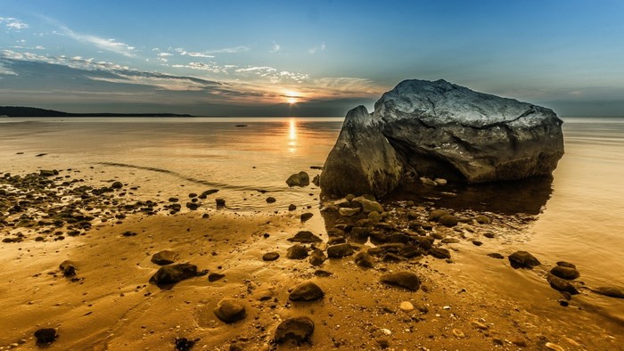 Sunset over the sea with rocks on the shore