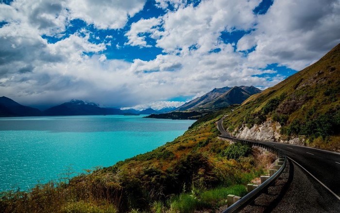Winding road along a turquoise lake and mountains