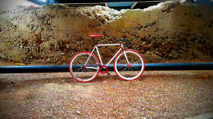 White fixie bicycle with red accents on gravel