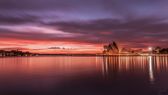 Sydney Opera House at sunset with colorful sky and water reflection