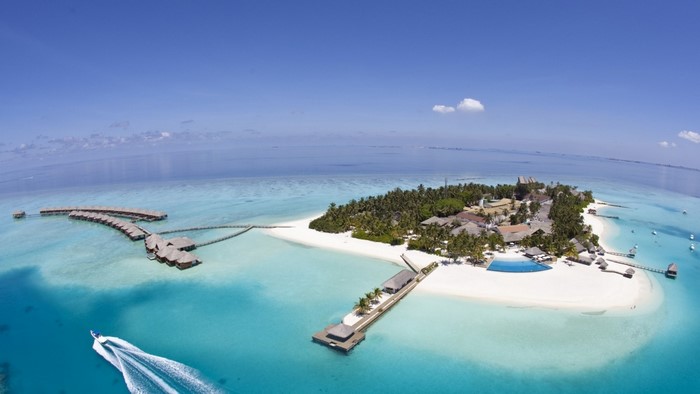 Aerial view of a tropical island resort with overwater bungalows