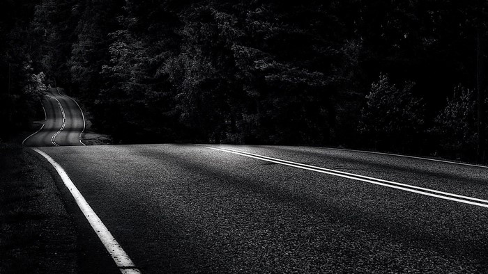 Winding road through dark forest at night