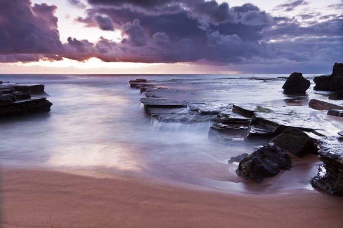 Sunset over rocky shore with ocean waves