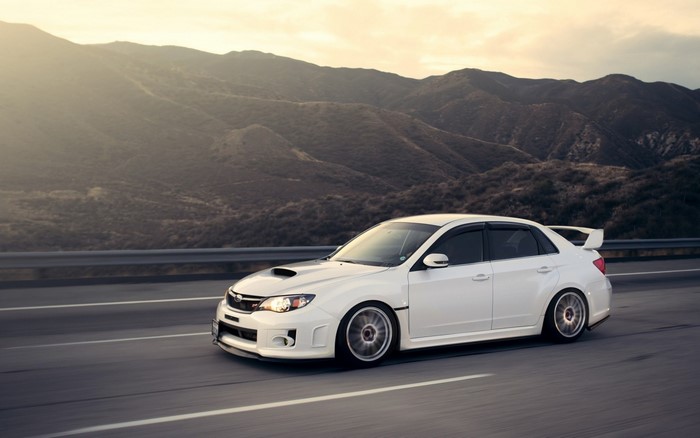 White Subaru WRX STI Sedan driving on a mountain road
